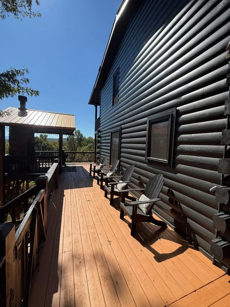 Freshly finished orange deck with Adirondack chairs beside a dark log cabin wall